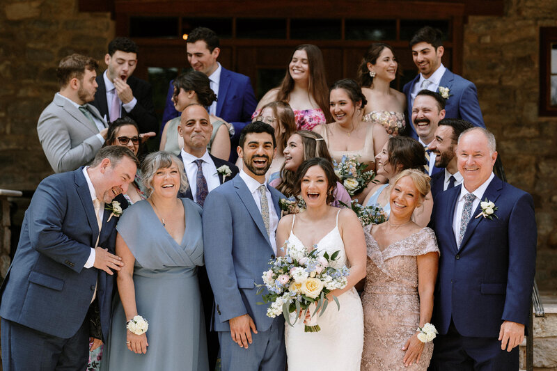 A candid photo of a family posing joyfully in front of a charming stone house, capturing a moment of celebration.