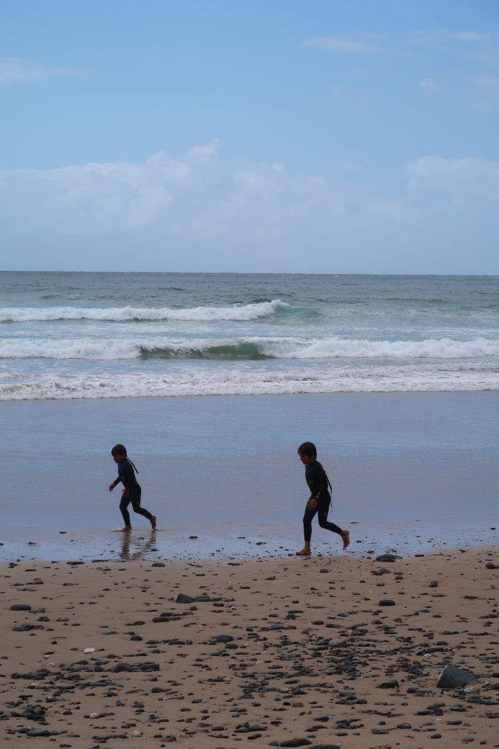 Two kids running on a beach in the Algarve