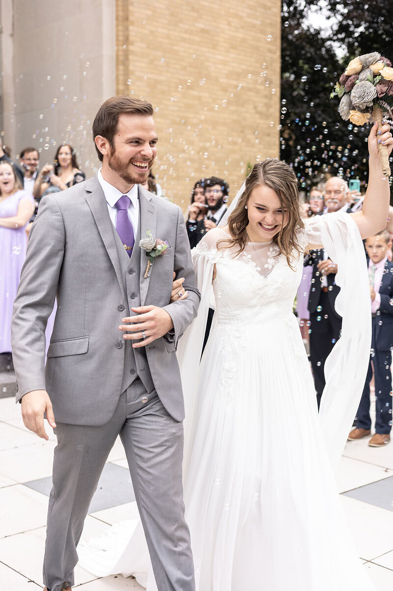 Newlyweds exit St. Sebastian's Catholic Church in Akron, OH amid joyful laughter and bubbles