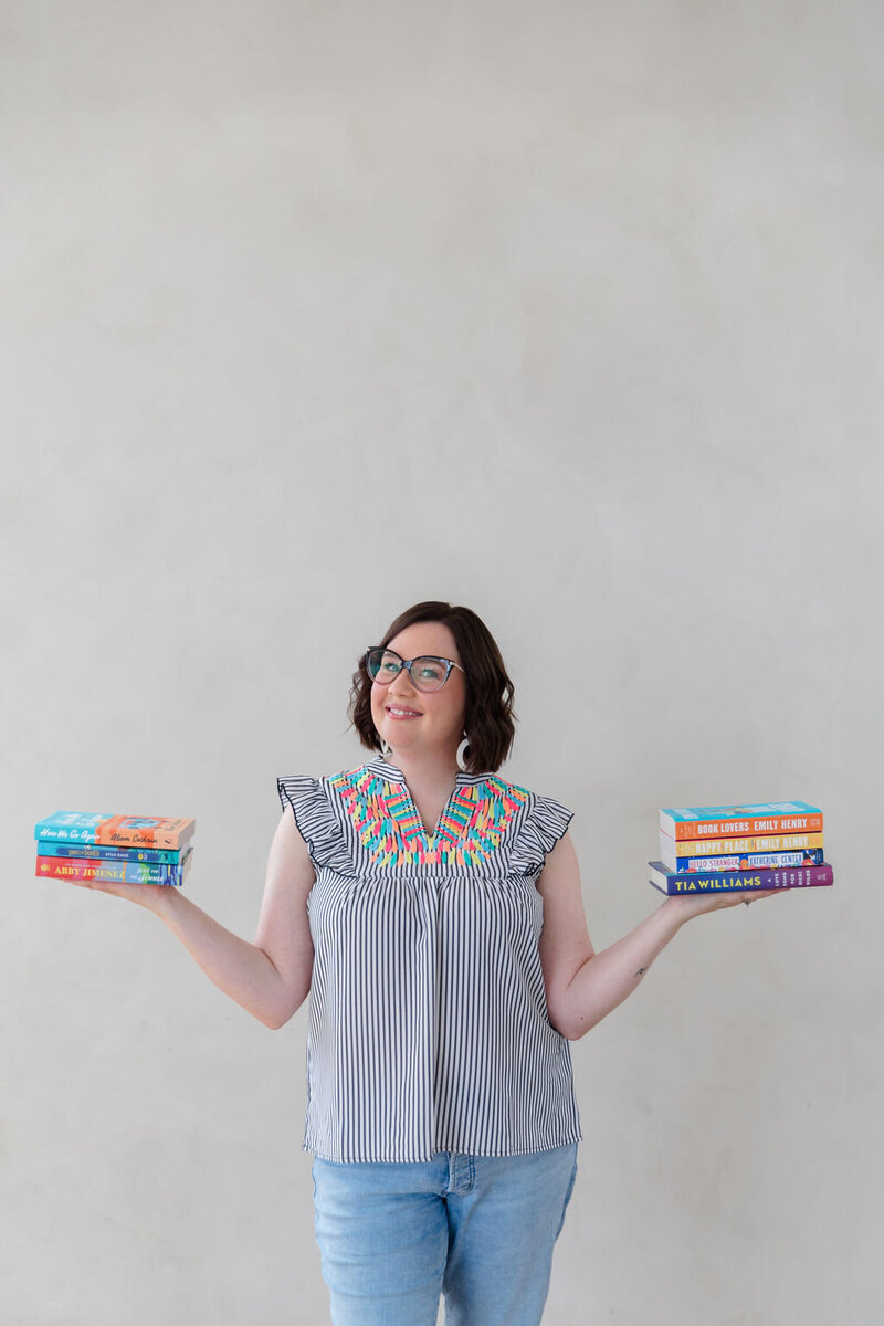 Bookstore owner Sara Gillis holding a pile of books in her outstretched hands