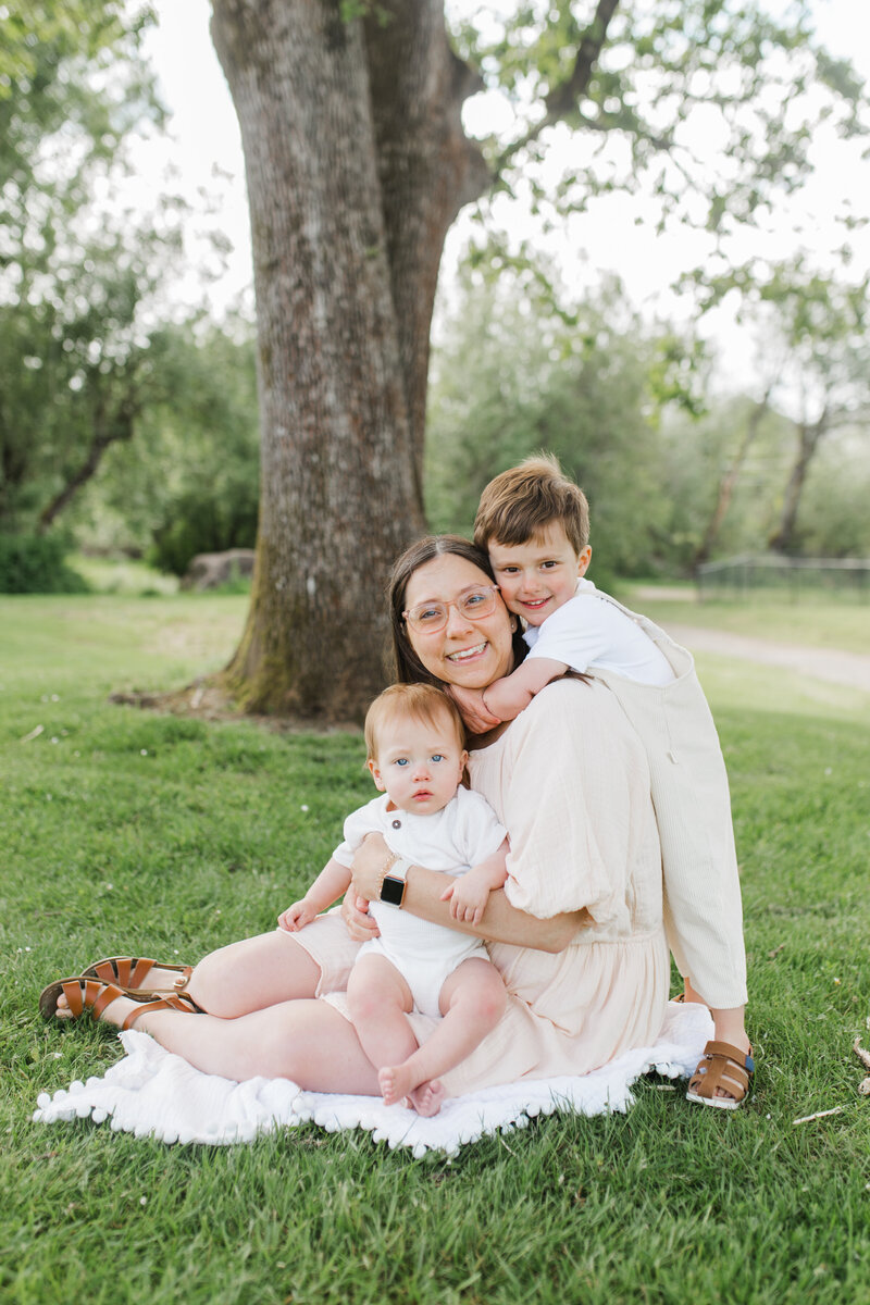 Mother sitting with two children under a tree