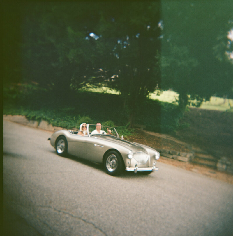 Bride stepping into a vintage car outside Hotel Domestique’s scenic estate.
