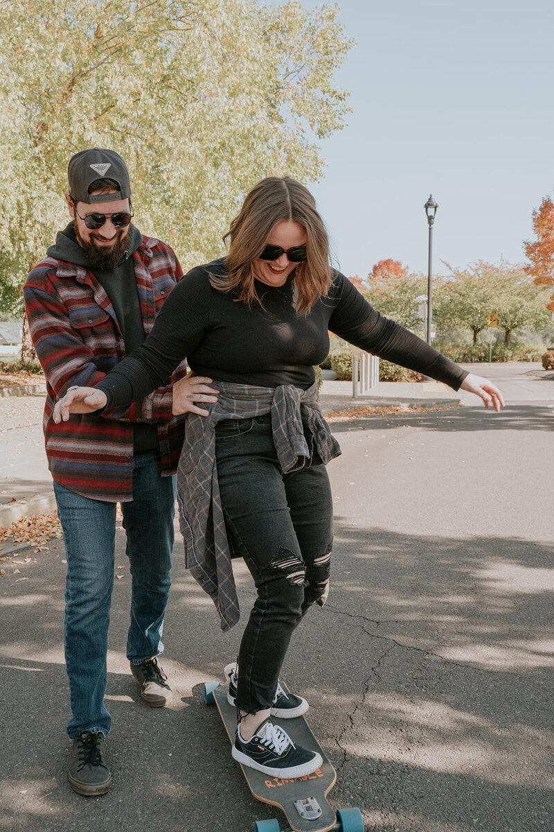 Couple session having fun playing with a skateboard. 