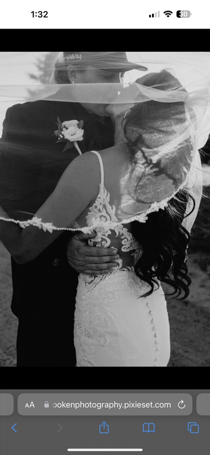 Black and white close-up of a groom holding the bride, with veil detail