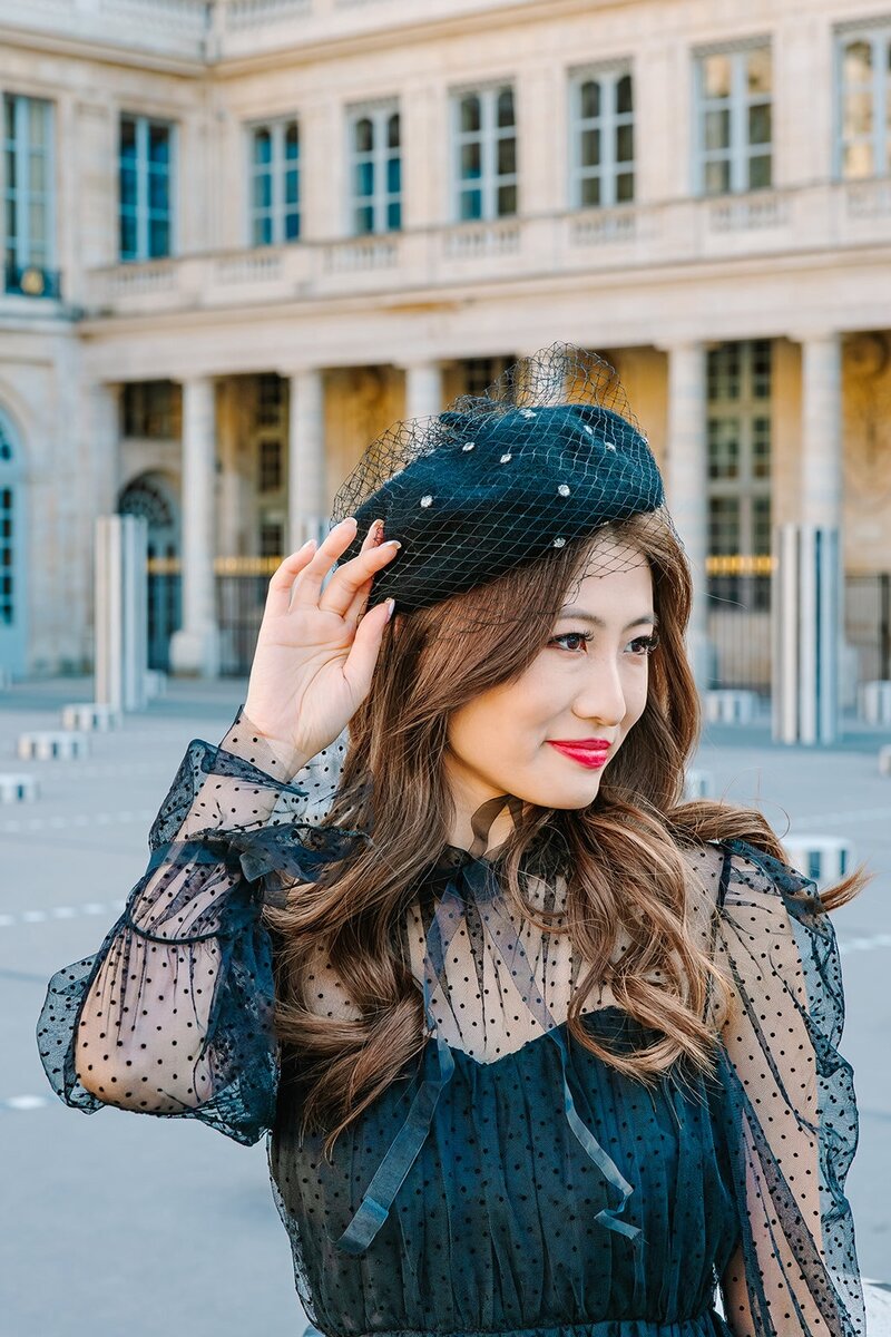 Solo woman adjusting her beret during a fashionable Paris photoshoot near the Eiffel Tower, Louvre, and Palais Royal.