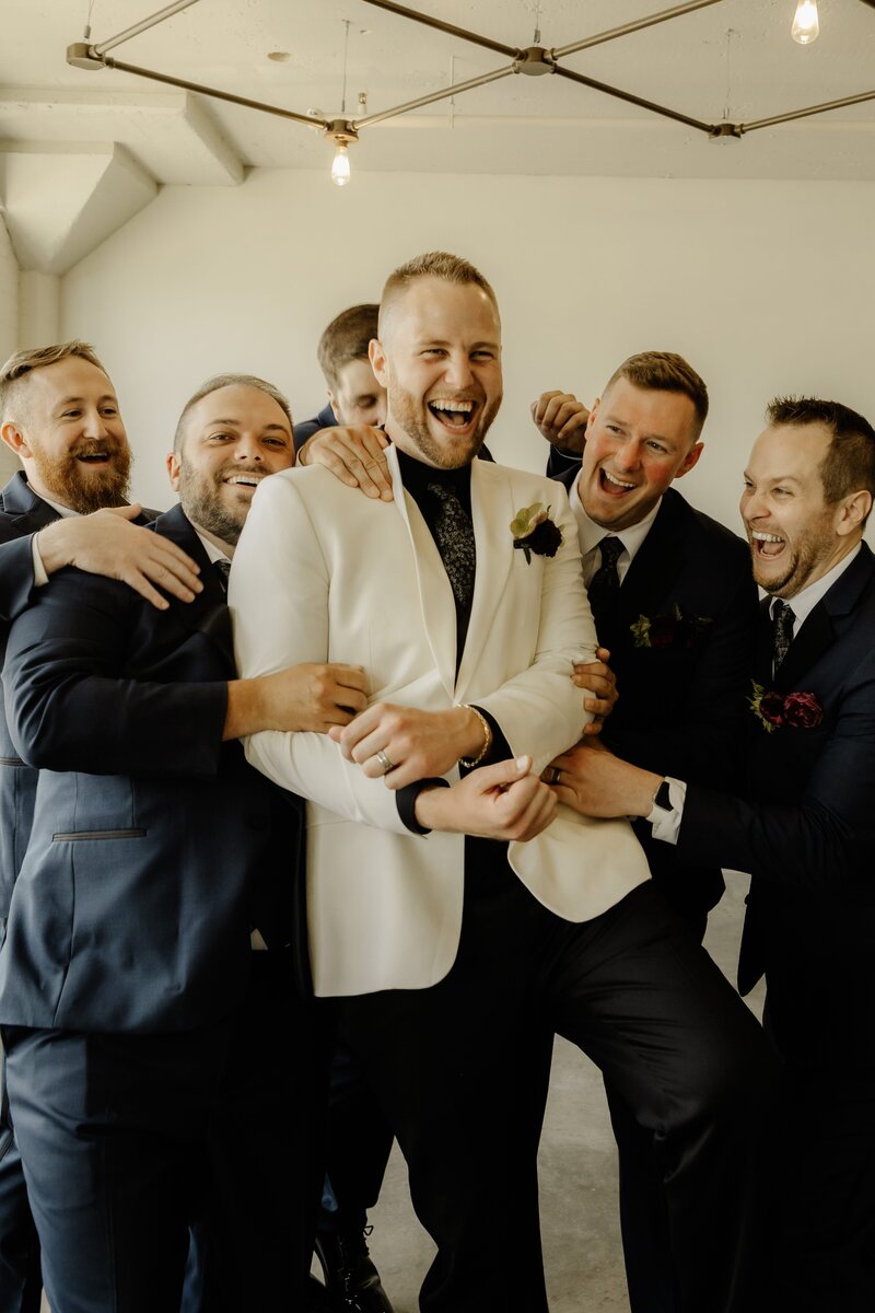 Excited groomsmen congratulate their friend who is the groom.