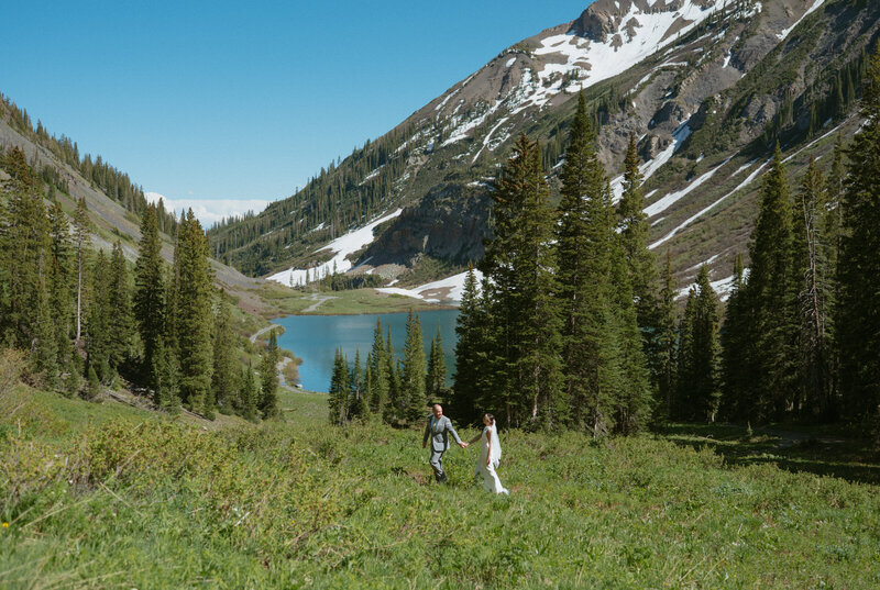 A couple stands at an alpine lake during their Colorado elopement ceremony with their closest family and friends
