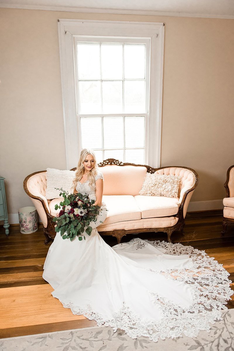 Bride siting on vintage pink couch inside the Drakewood Farm bride suite