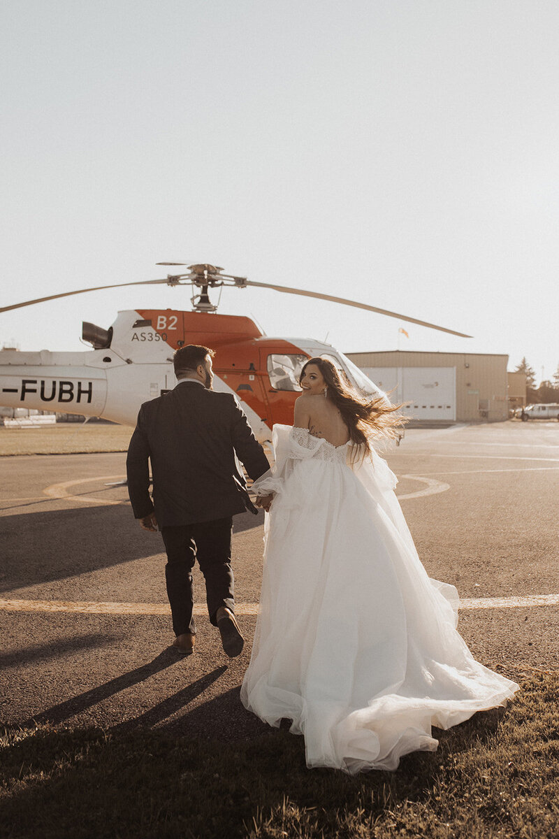 Couple running towards a helicopter.
