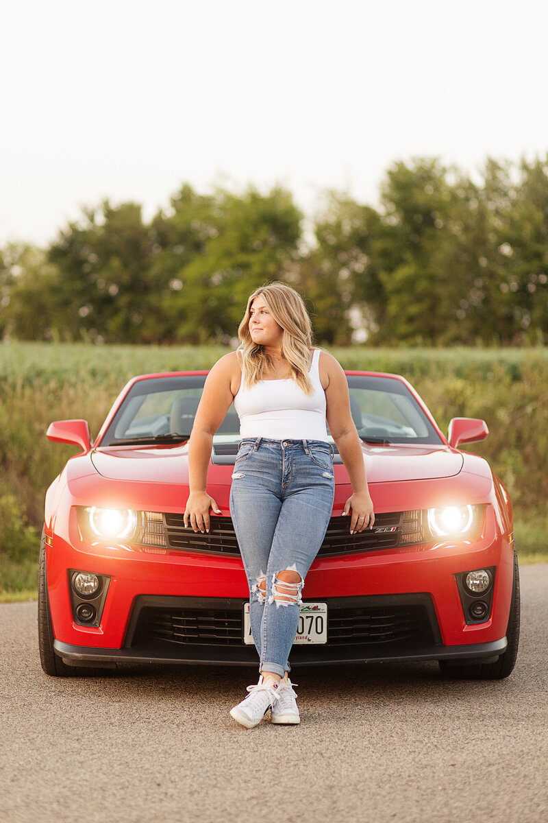 Girl leaning against the front of her sports car