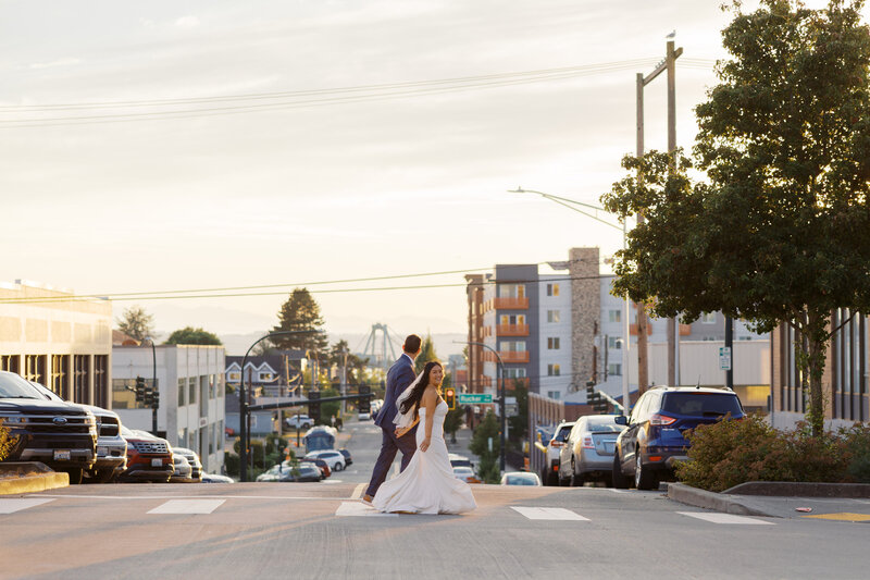 bride and groom walking across the street laughing in everett, washington