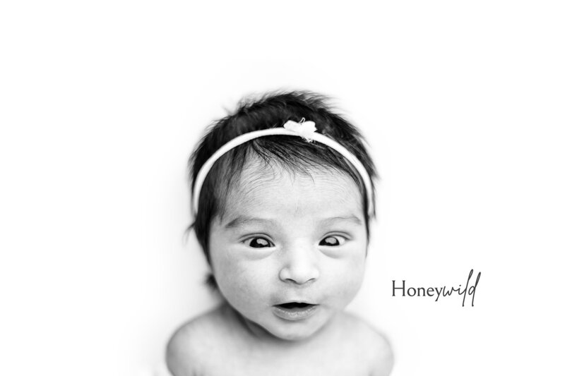 Newborn photographer in Grand Rapids captures swaddled baby looking surprised with headband