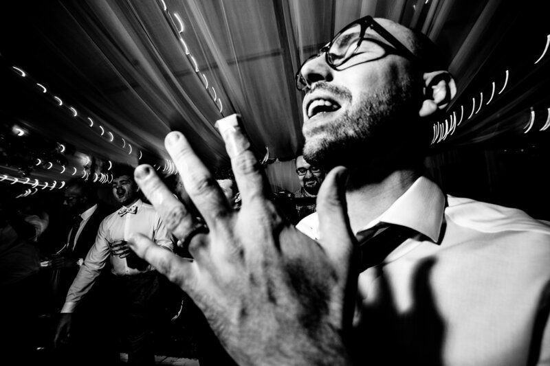 A groom dancing at the wedding with his hand held up