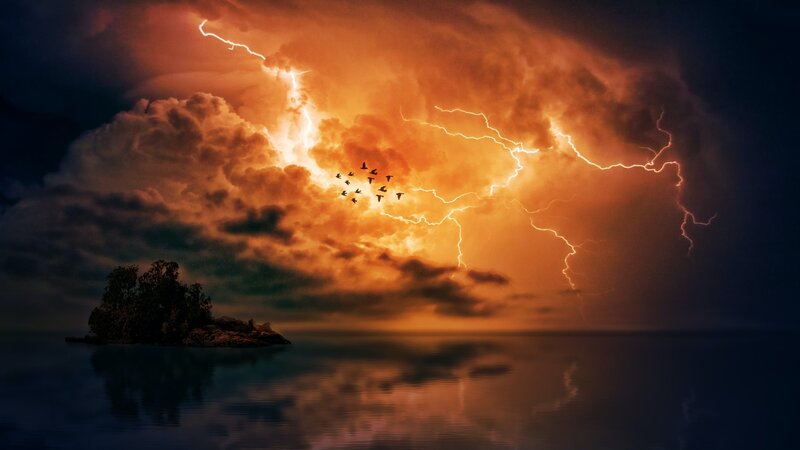 lightning streaking across the sky above water and a small island