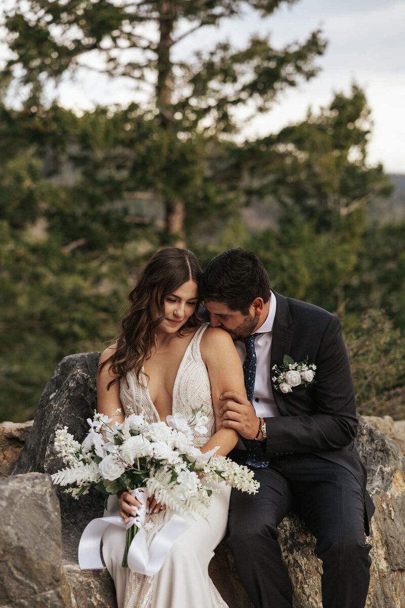 A person kissing their partner's shoulder on their wedding day.