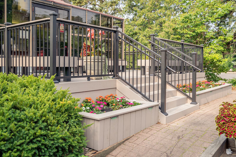 Front steps of composite deck at Adele's Frozen Custard with aluminum railing and integrated planters. 