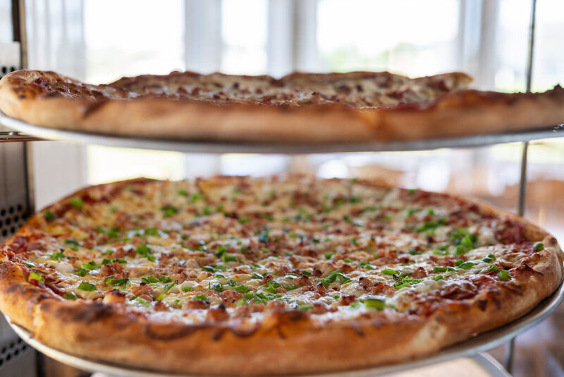 Stack of hot, cheesy Redo’s pizzas fresh from the oven—family specials and deals served in Yarmouth and Wolfville