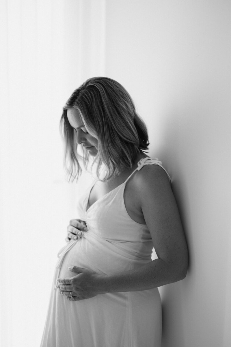 Black and white image of pregnant mother looking down at her belly sweetly as photographed by Sydney maternity photographe