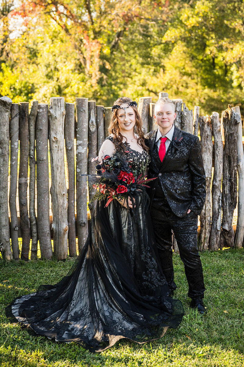 A lesbian couple stands in the backyard of an Airbnb and poses together for a photo on their elopement day.