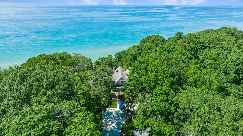 A breathtaking aerial shot showcasing custom high-end homes along the long shore. The image captures the elegance and luxury of these waterfront properties, highlighting their prime location and stunning architecture.