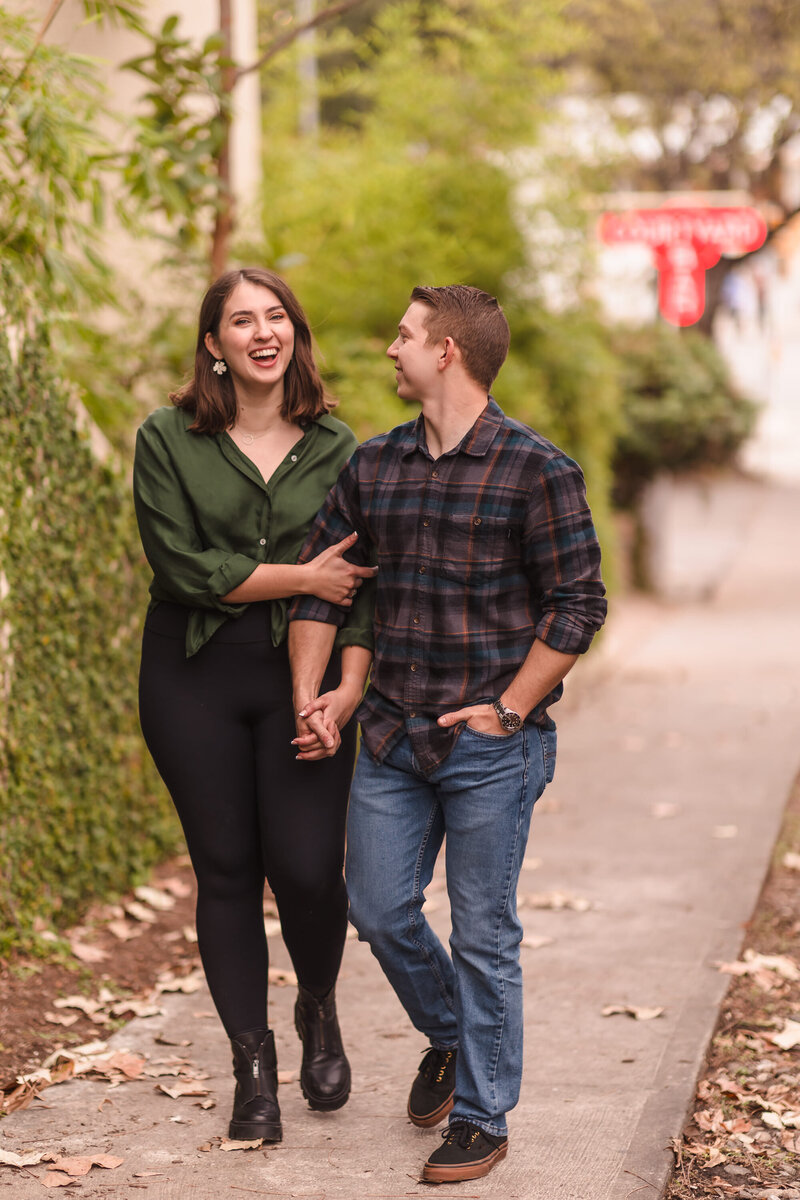 Couple walk down the street during their engagement session in Austin, Texas. Photo taken by Austin Engagement Photographers, Joanna & Brett Photography