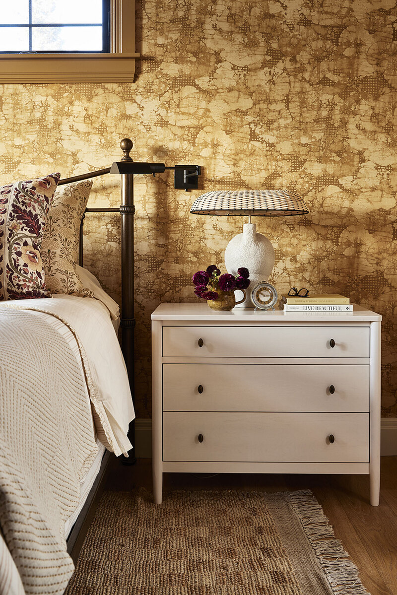 close up of a white bedside table in a bedroom with an interesting beige and brown textured wallpaper