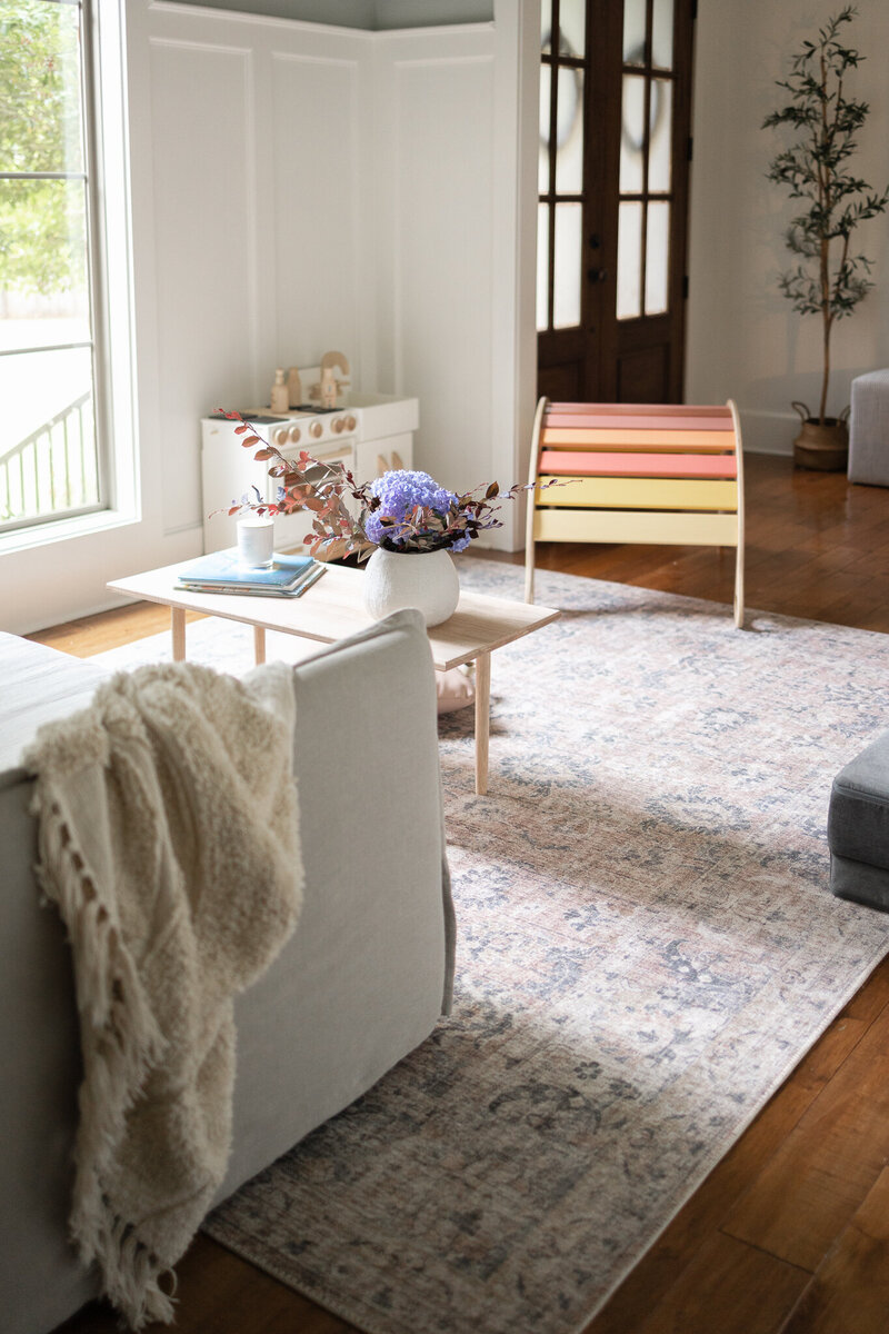 looking into a family friendly living space with a loloi vintage inspired rug, wiwiurka sunset rocker, DIY table, milton and goose play kitchen, and six penny neva sofa