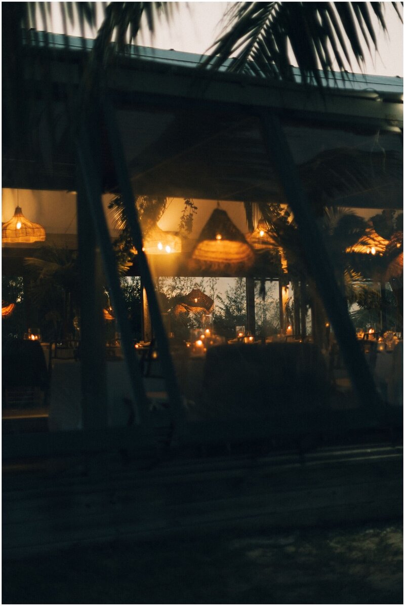 A look through the window to a low lit tropical wedding reception