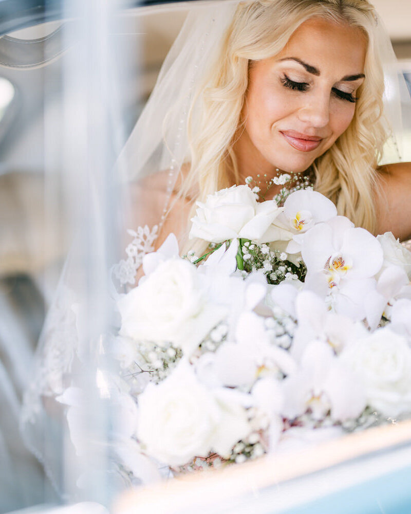This beautiful photograph captures a bride seated in a luxury car, radiating elegance and sophistication as she prepares for her special day.