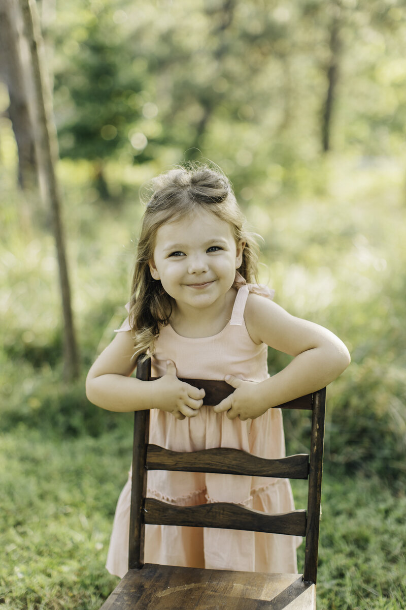 photo of a girl smiling while holding a chair