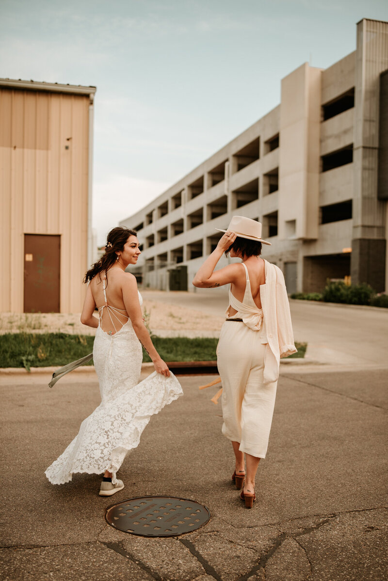 gay brides walking down the street away from camera