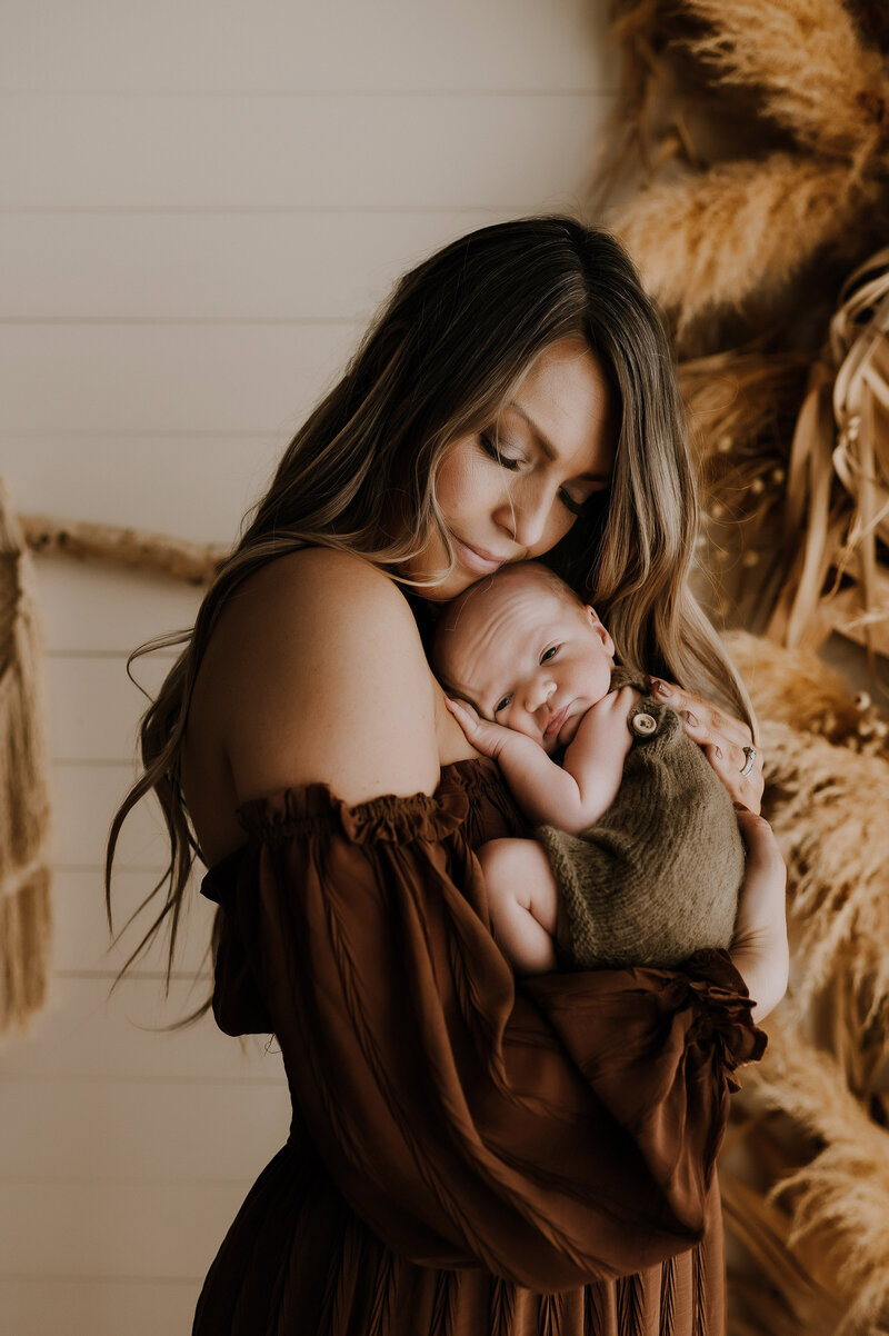 A mom holding a newborn baby in a photography studio in Fort Worth Texas