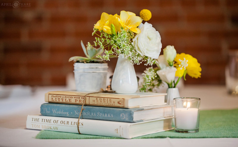 VIntage book wedding themed centerpieces with yellow flowers with the exposed red brick walls inside the Boulder Museum of Contemporary Art
