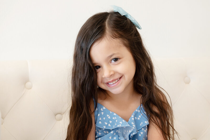 little girl in blue and white dress on cream couch