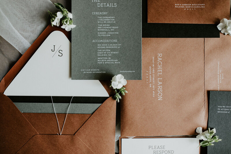 White curved menu card on a plate with a brown velvet napkin and flowers