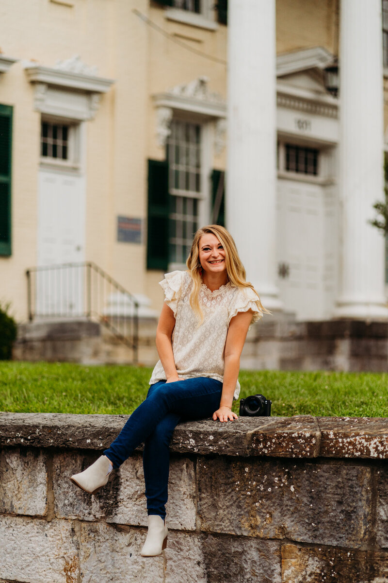 Staci is sitting on courthouse steps with a bright smile, ready to help couples plan their dream elopement