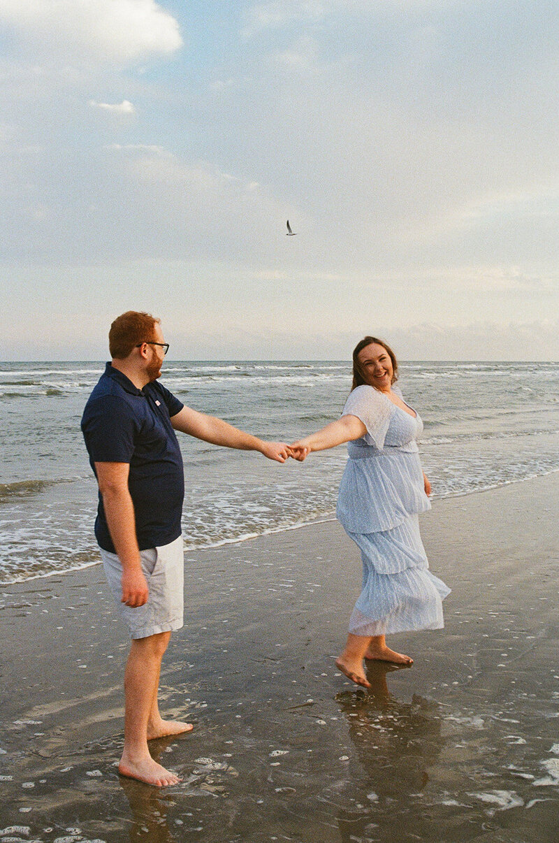 A couple dance at Galveston Island Beach during an engagement photo session