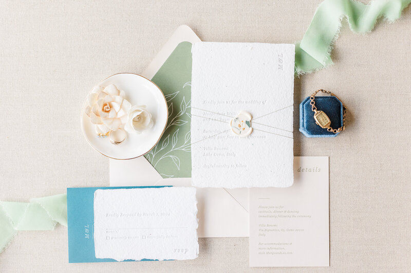 Wedding details on display on a table with invitations and jewelry