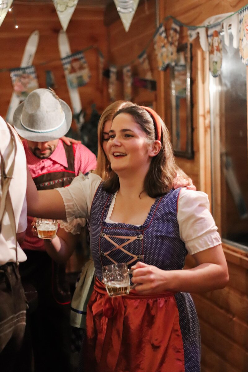 Lachende vrouw in dirndl outfit met bierglas tijdens een Oostenrijks themafeest