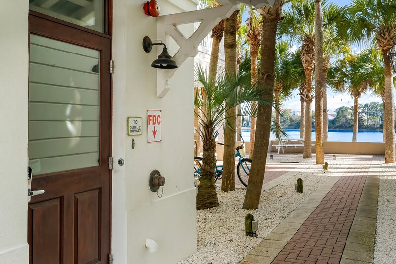 Private entrance to The Florida House vacation rental with palm-lined pathways and peaceful Lake Carillon views. Prime spot near Panama City Beach and 30A beach rentals.