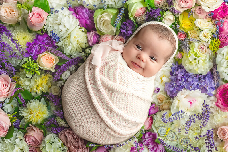 A radiant newborn portrait bursting with personality and petals—styled in soft floral tones.