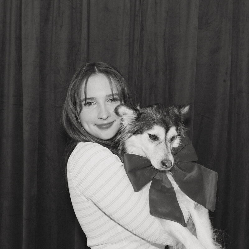 A black and white photo of Hannah with her dog in her home studio, capturing a quiet and artistic moment.