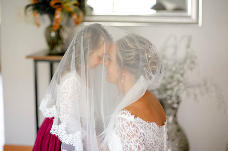 Bride and daughter having a moment under wedding veil