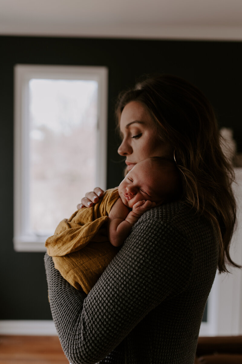 Newborn baby rests on mom's shoulder.