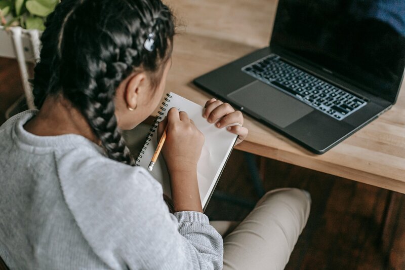 girl with french braids in hair writing in notebook