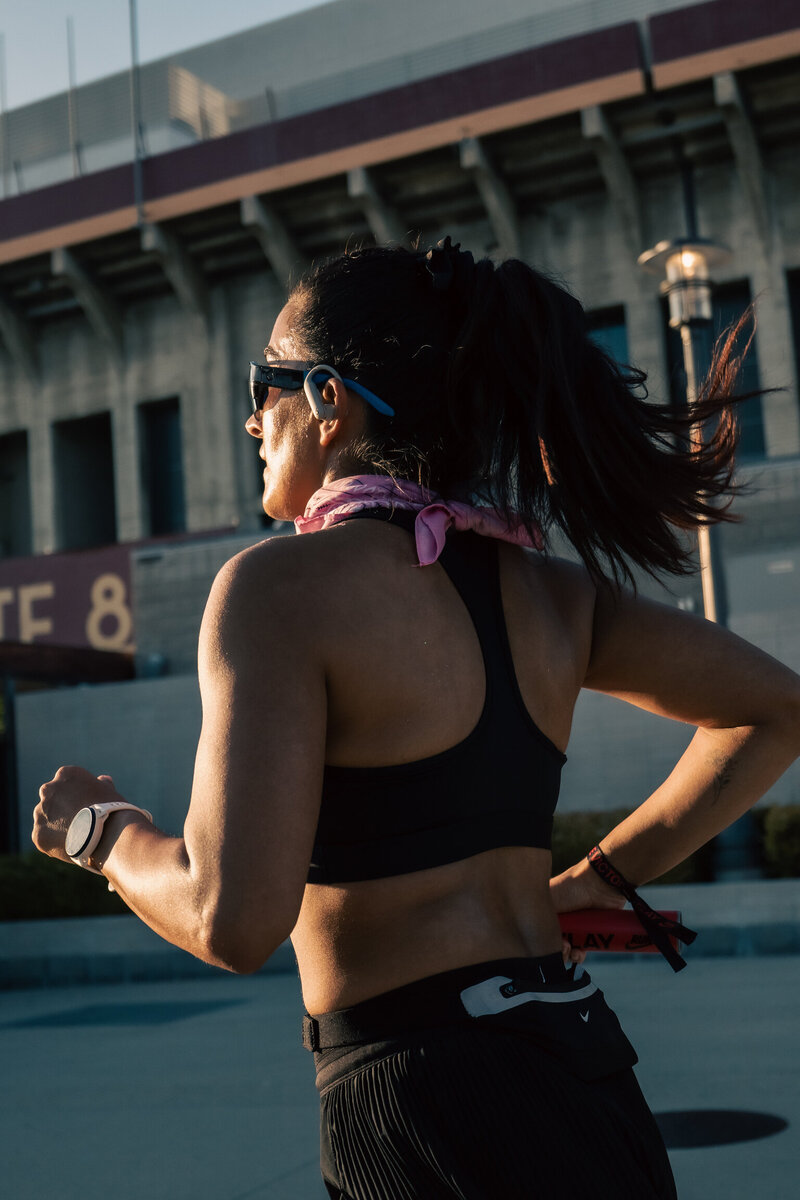 Back view of a HER Sports athlete running outdoors in the early morning light.