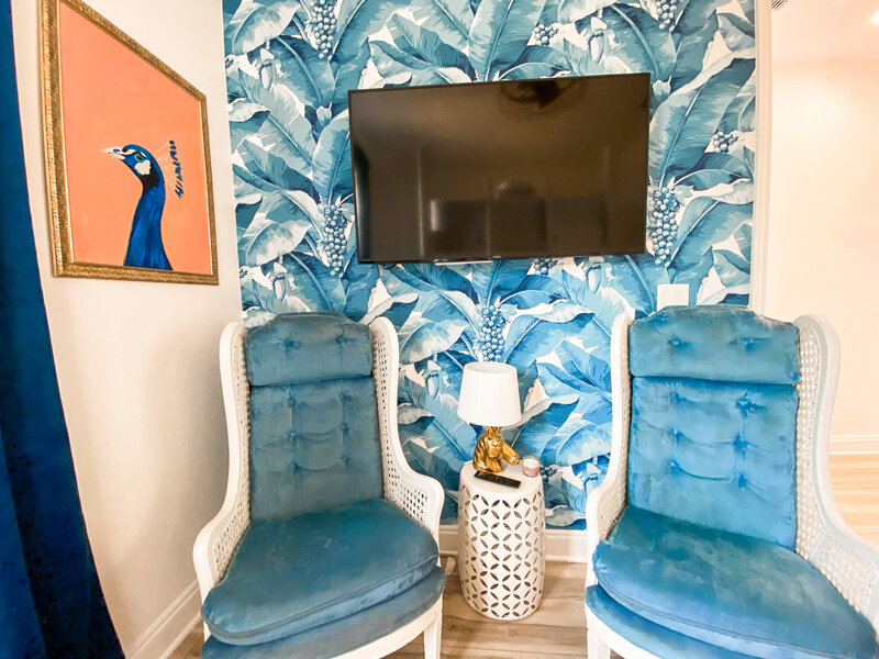 bedroom with blue palms wallpaper and vintage blue chairs