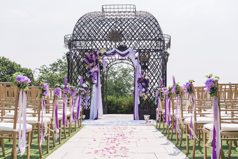 An outdoor reception event with beautiful purple theme floral decoration at the gazebo.
