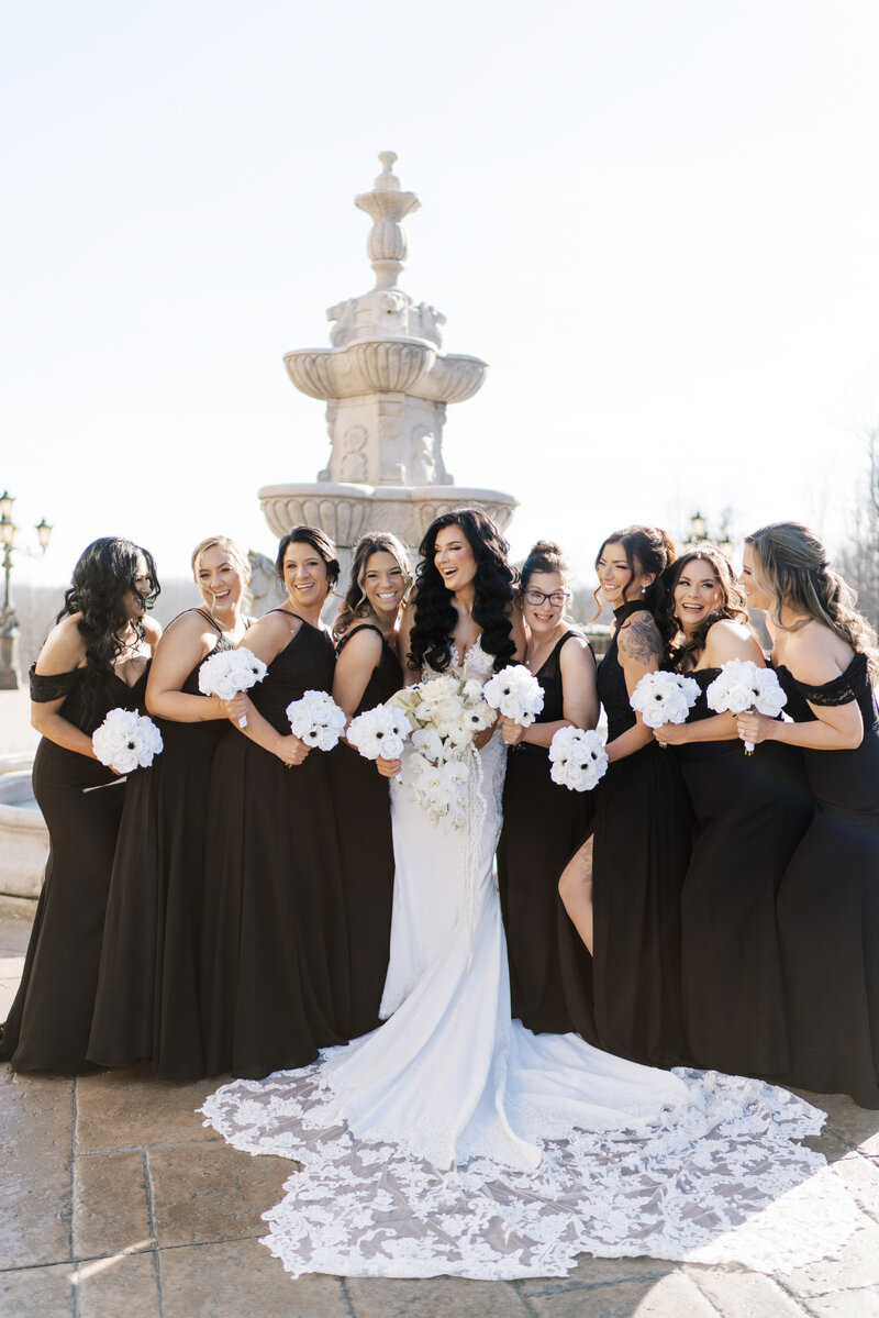 A black and white detail photo of a bride holding up her dress.