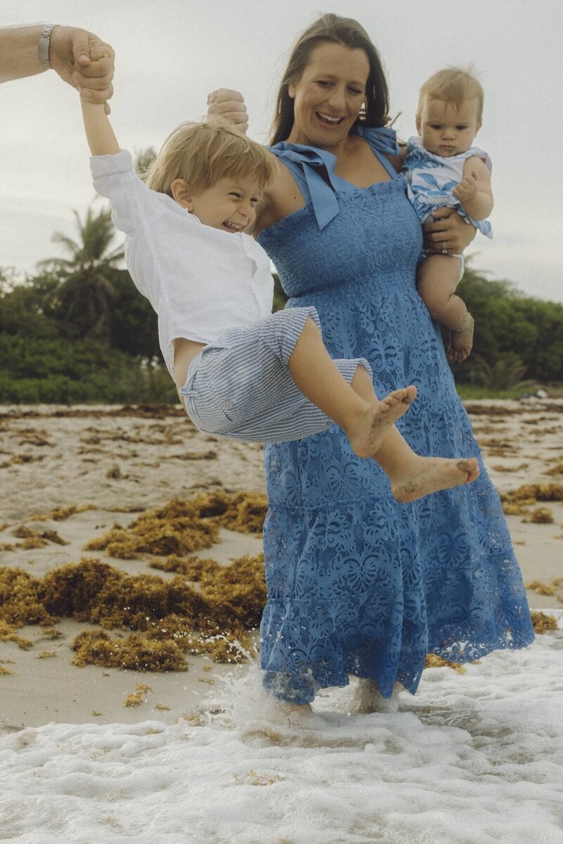 mom plays with her children on the beach